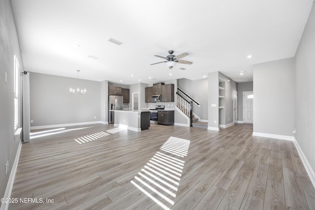 unfurnished living room featuring ceiling fan with notable chandelier, sink, and light hardwood / wood-style flooring