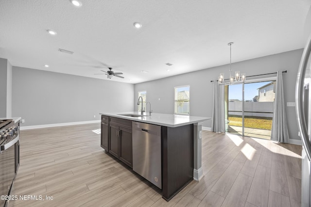 kitchen with decorative light fixtures, stainless steel appliances, a center island with sink, ceiling fan with notable chandelier, and sink