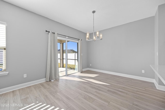 unfurnished room featuring light hardwood / wood-style flooring and a chandelier