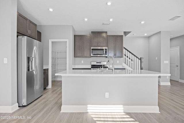 kitchen featuring stainless steel appliances, a center island with sink, light hardwood / wood-style flooring, and sink