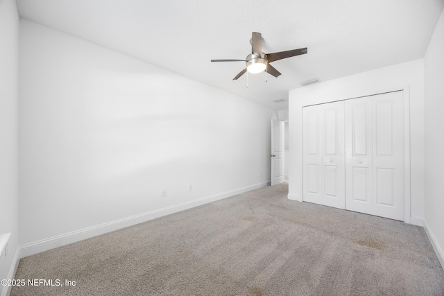 unfurnished bedroom featuring light colored carpet, ceiling fan, and a closet