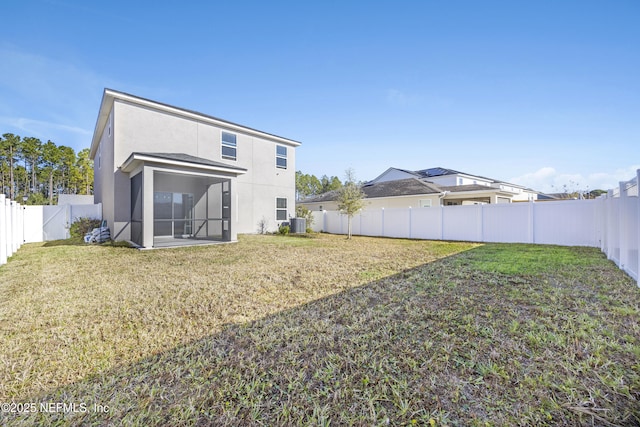 rear view of property featuring a lawn, central AC unit, and a sunroom