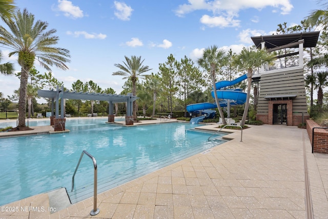 view of pool with a water slide, a patio area, and a pergola