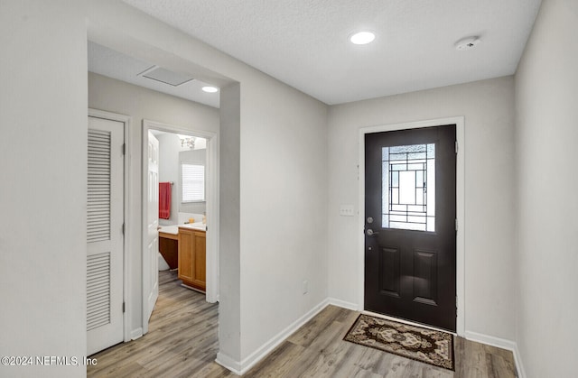 entrance foyer featuring light wood-type flooring, a textured ceiling, and a healthy amount of sunlight