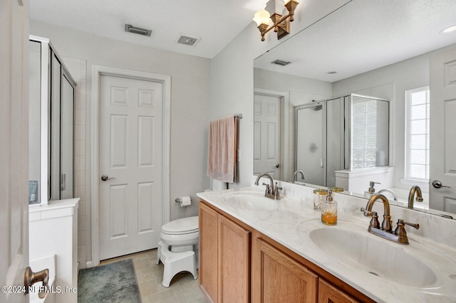 bathroom with toilet, vanity, a textured ceiling, and a shower with shower door