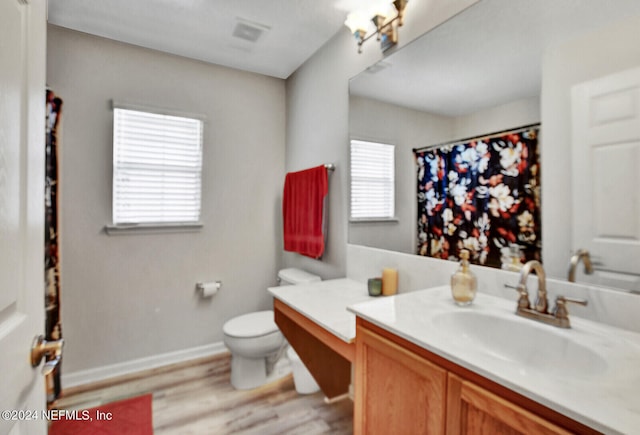 bathroom featuring toilet, vanity, hardwood / wood-style flooring, and a wealth of natural light