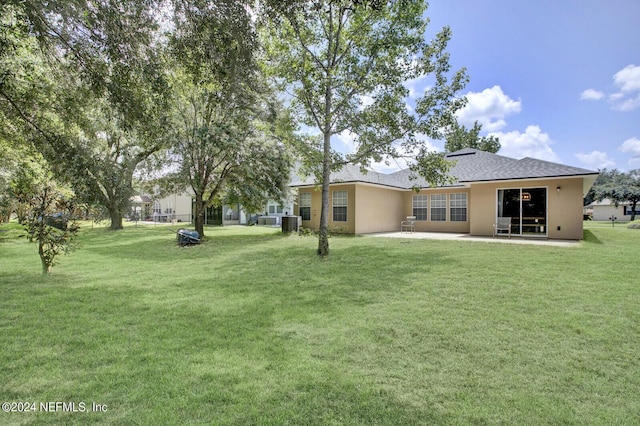 back of property with central air condition unit, a patio, and a yard