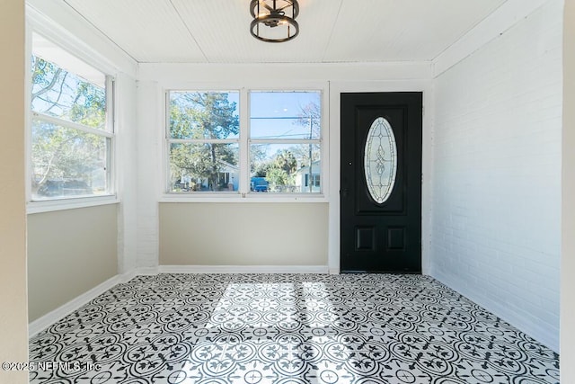 foyer featuring brick wall