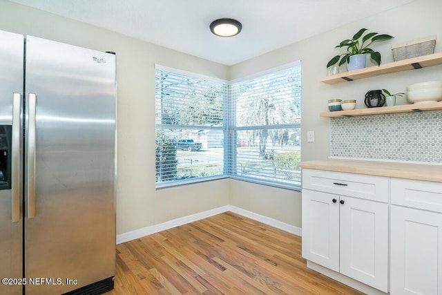 kitchen featuring white cabinetry, light hardwood / wood-style floors, wood counters, stainless steel refrigerator with ice dispenser, and plenty of natural light