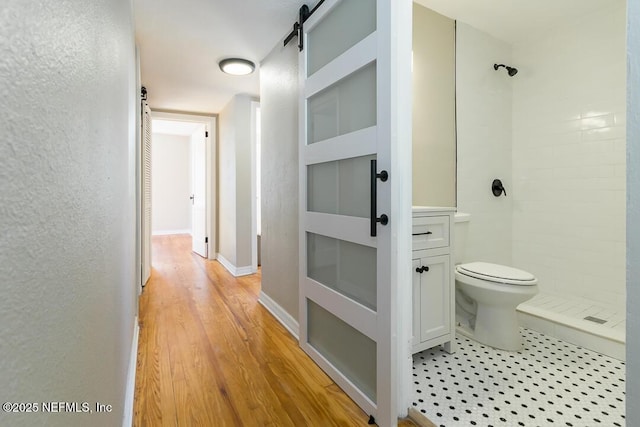 bathroom featuring toilet, a shower, and hardwood / wood-style floors