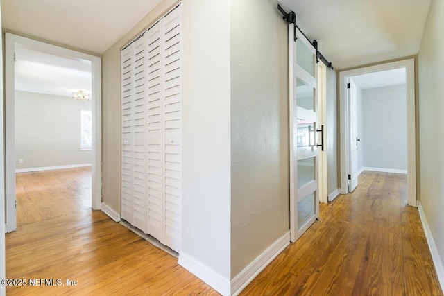 corridor with a barn door and wood-type flooring