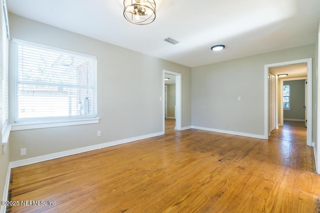 empty room with light wood-type flooring and an inviting chandelier