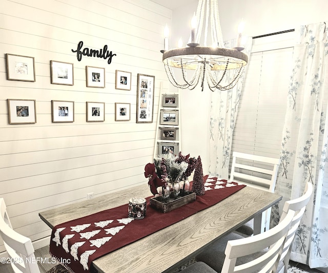 dining space featuring wood walls and an inviting chandelier