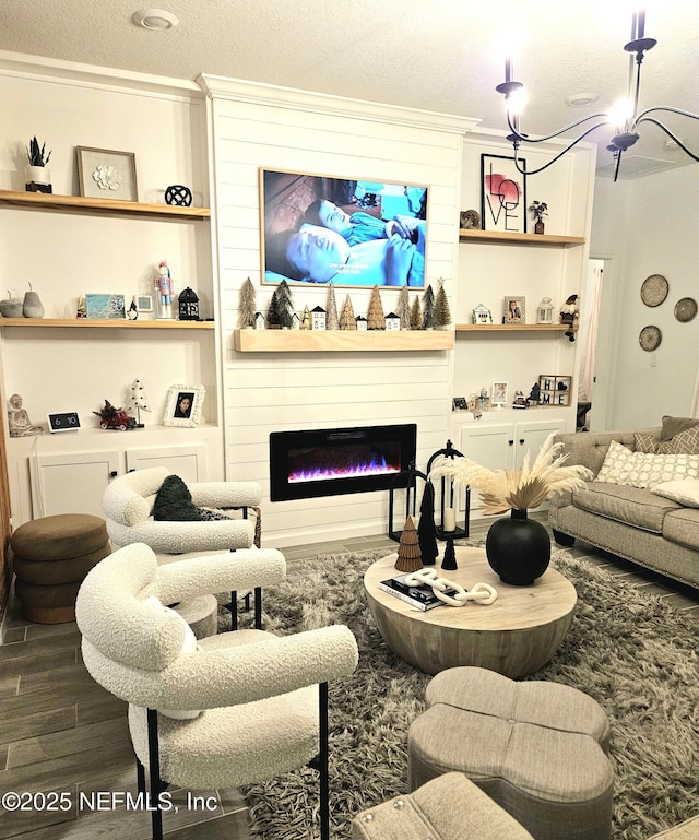 living room featuring wood-type flooring, a large fireplace, a textured ceiling, and ornamental molding