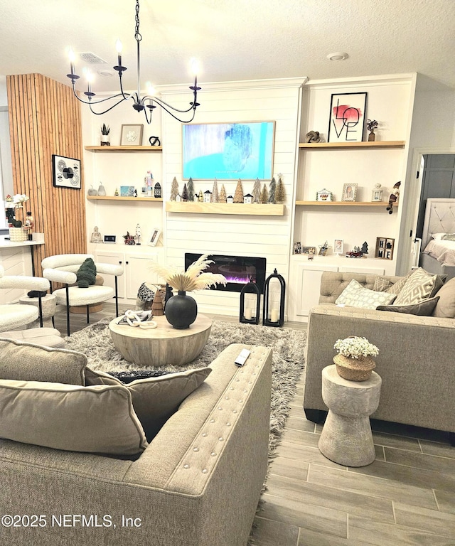 living room with a fireplace, a textured ceiling, and an inviting chandelier