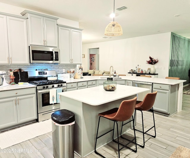 kitchen with a breakfast bar, a center island, sink, appliances with stainless steel finishes, and kitchen peninsula