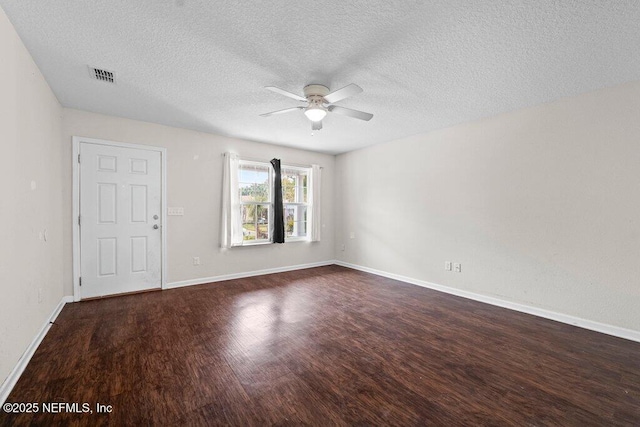 spare room featuring ceiling fan, a textured ceiling, dark wood-type flooring, visible vents, and baseboards