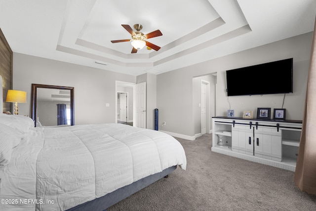 carpeted bedroom with ceiling fan and a raised ceiling