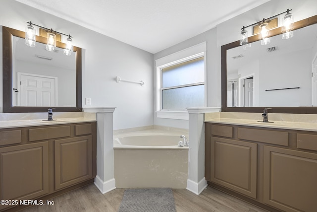 bathroom featuring hardwood / wood-style floors, a washtub, and vanity