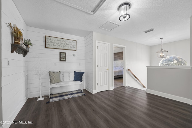 unfurnished room with a textured ceiling, dark hardwood / wood-style flooring, wood walls, and a notable chandelier