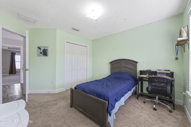 bedroom featuring light colored carpet, a closet, and a textured ceiling