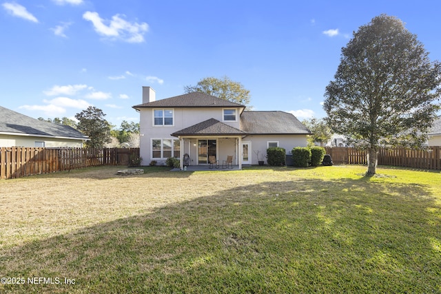 rear view of house featuring a yard, a fire pit, and a patio