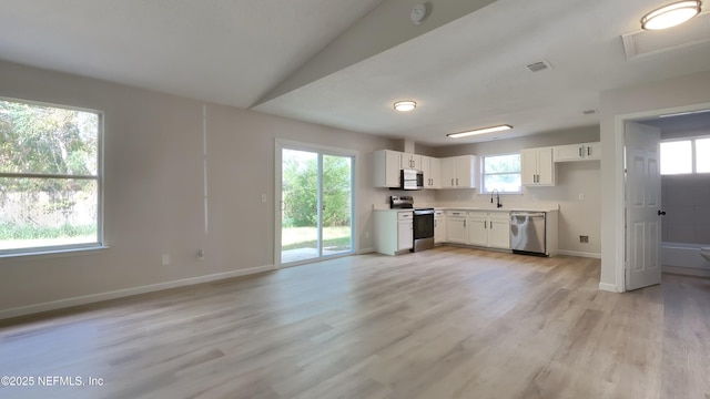 kitchen with stainless steel appliances, white cabinetry, a wealth of natural light, and light hardwood / wood-style flooring