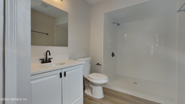 bathroom featuring hardwood / wood-style floors, vanity, toilet, and walk in shower