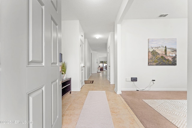 corridor featuring a textured ceiling and light tile patterned floors