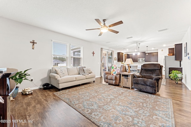 living room featuring ceiling fan, wood-type flooring, and a textured ceiling