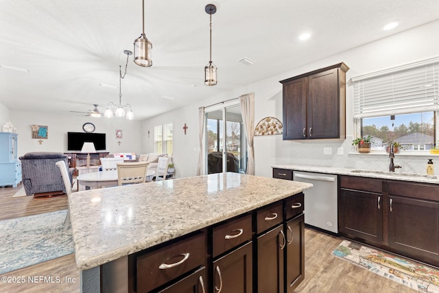 kitchen featuring sink, a center island, stainless steel dishwasher, light hardwood / wood-style floors, and decorative light fixtures