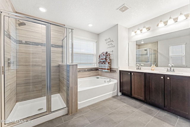 bathroom featuring plus walk in shower, vanity, a textured ceiling, and tile patterned floors