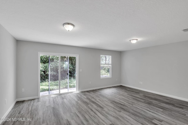 spare room with a textured ceiling and dark hardwood / wood-style flooring