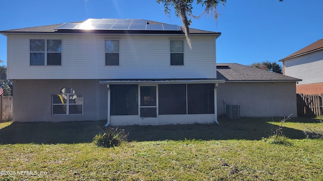 back of house with a yard, central air condition unit, a sunroom, and solar panels