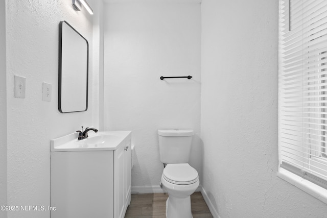 bathroom with toilet, vanity, and hardwood / wood-style floors