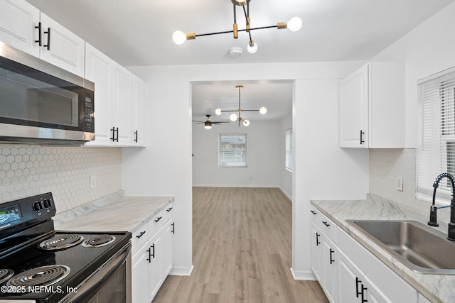 kitchen with light hardwood / wood-style floors, black electric range, decorative light fixtures, white cabinets, and sink