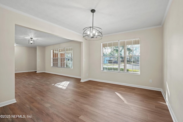 empty room featuring dark wood-type flooring, a textured ceiling, ornamental molding, and a notable chandelier