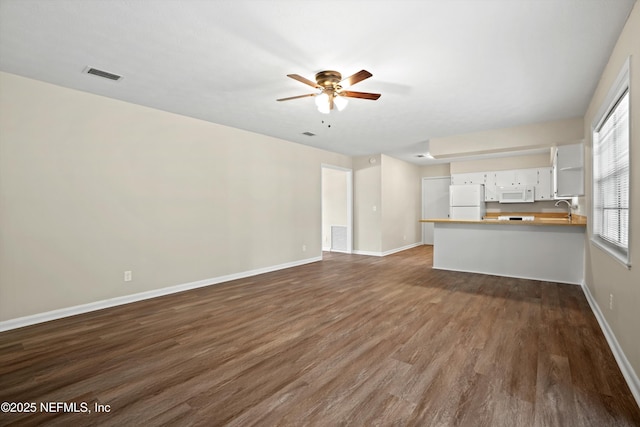unfurnished living room featuring ceiling fan, sink, and dark hardwood / wood-style flooring