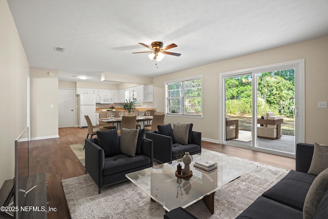 living room featuring ceiling fan, a textured ceiling, and dark hardwood / wood-style flooring