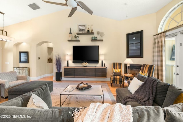 living room featuring a fireplace, light wood-type flooring, vaulted ceiling, and ceiling fan