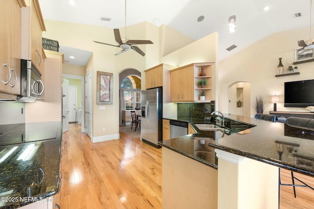 kitchen with kitchen peninsula, a breakfast bar, stainless steel appliances, and dark stone countertops