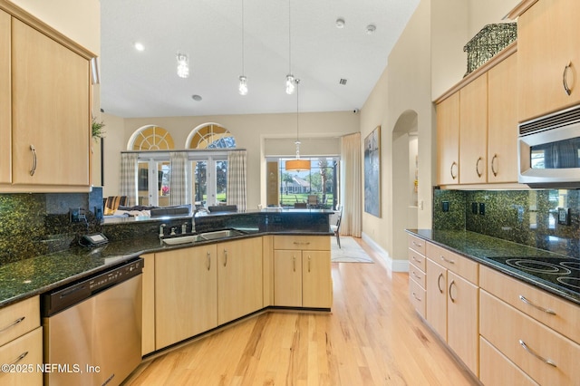 kitchen featuring appliances with stainless steel finishes, sink, light brown cabinets, pendant lighting, and dark stone countertops