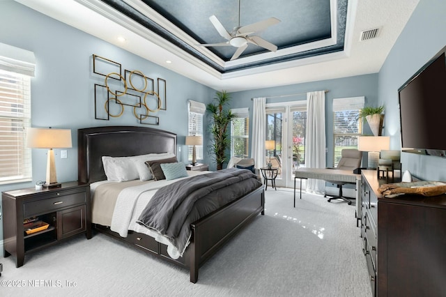 carpeted bedroom with a raised ceiling, ceiling fan, and crown molding