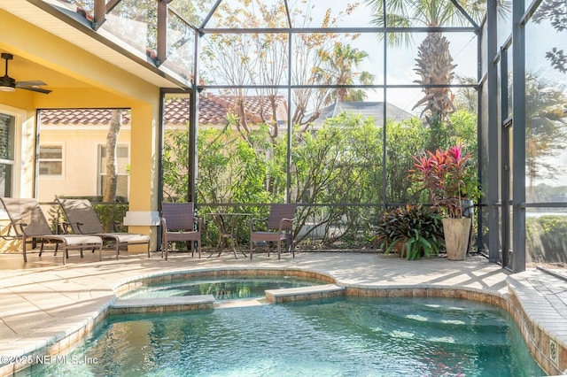 view of pool with a lanai, ceiling fan, a patio area, and an in ground hot tub