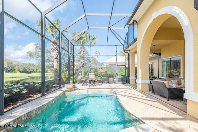 view of swimming pool featuring ceiling fan, a lanai, an outdoor living space, a water view, and a patio