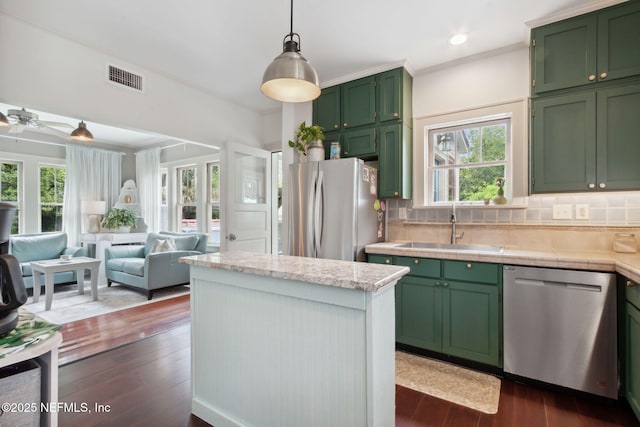 kitchen featuring stainless steel appliances, green cabinetry, sink, tasteful backsplash, and dark hardwood / wood-style floors