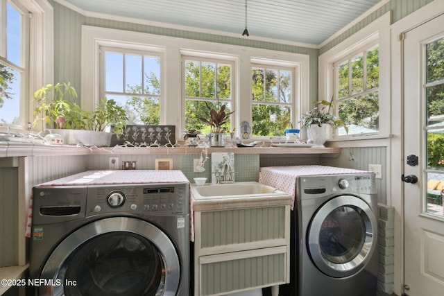 clothes washing area with ornamental molding, separate washer and dryer, and sink