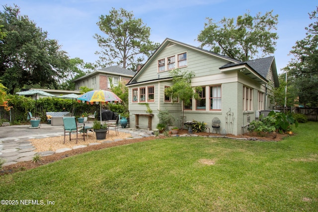 rear view of property with a lawn, a garage, and a patio area