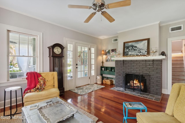 living room featuring a brick fireplace, ceiling fan, hardwood / wood-style floors, and crown molding