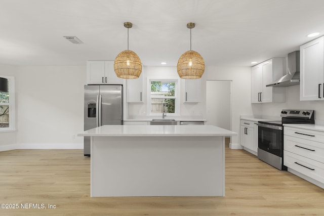 kitchen featuring appliances with stainless steel finishes, wall chimney range hood, white cabinetry, and a center island